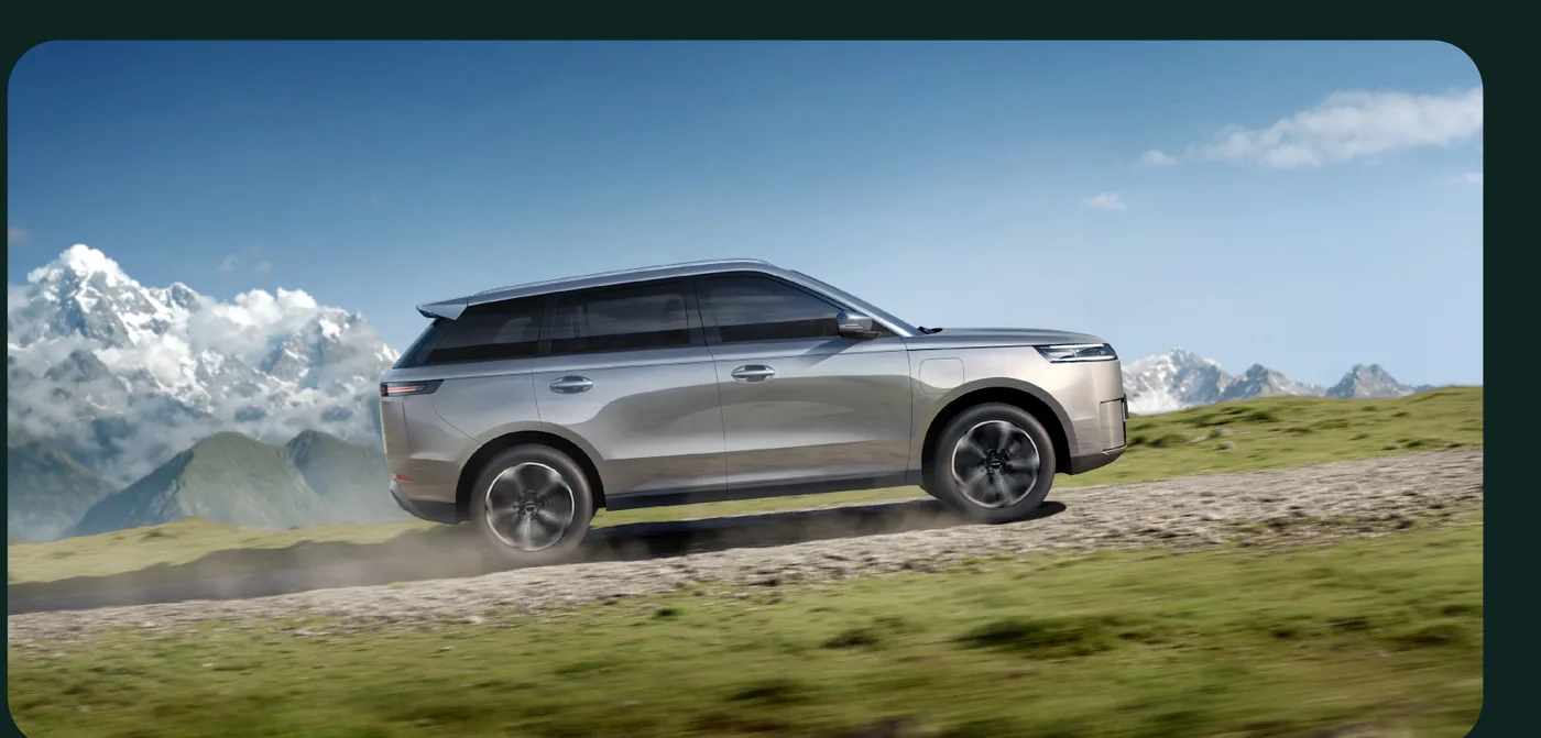 Jaecoo J5 EV driving on a mountain track with snow-capped peaks behind.