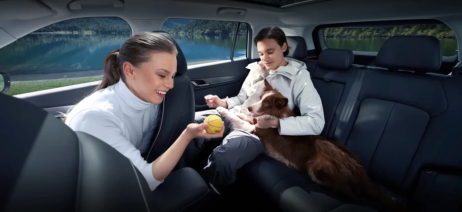 Two passengers playing with a dog on the rear bench of the Jaecoo J5 EV, a lake outside the window.